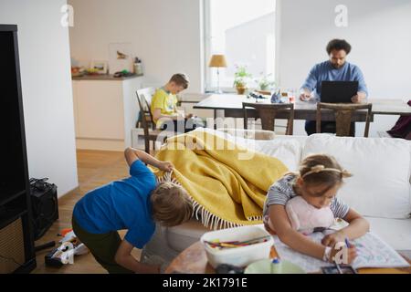 Children playing while father working from home Stock Photo