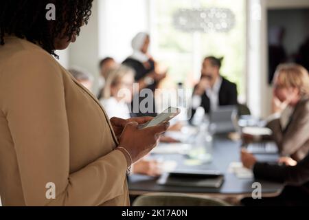 Woman using cell phone during business meeting Stock Photo