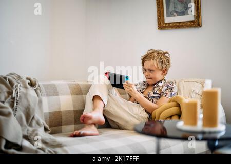 Boy on sofa using digital tablet Stock Photo