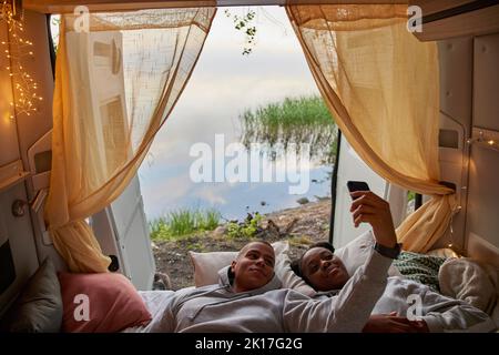 Young couple taking selfie in camper van Stock Photo