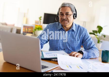 Senior biracial man using laptop and headset making video call Stock Photo