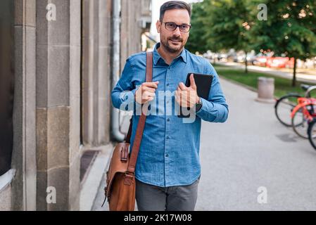 Ambitious adult businessman, coming to work, taking his personal tablet. Stock Photo