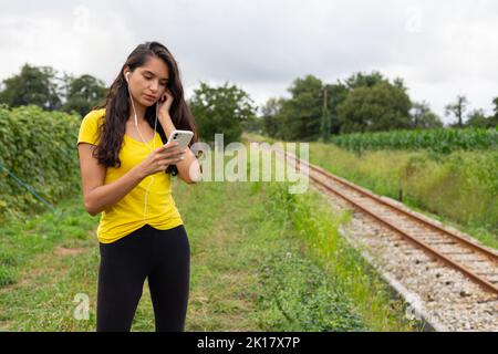 Content young ethnic lady listening to song and using smartphone in nature Stock Photo
