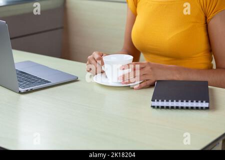 Crop freelancer enjoying hot drink in cafe Stock Photo
