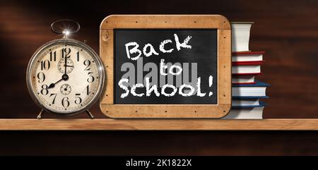 Back To School, close-up of an old alarm clock on a wooden shelf with a blackboard with wood frame and a stack of school books. Stock Photo