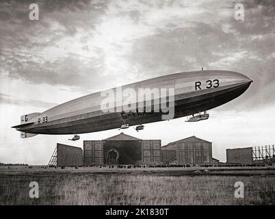 Airship R33 a British rigid airship, flying over its hanger at  RAF Pulham in Norfolk, England in 1925. The airships were built by Armstrong Whitworth for the Royal Naval Air Service during the First World War, but were not completed until after the end of hostilities, by which time the RNAS had become part of the Royal Air Force. Her first flight was in early 1919 then sent to Pulham airship station she clocked up over 300 flying hours in tests and the training of crew. Stock Photo