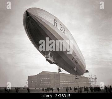 Airship R33 a British rigid airship, flying over its hanger at  RAF Pulham in Norfolk, England in 1925. The airships were built by Armstrong Whitworth for the Royal Naval Air Service during the First World War, but were not completed until after the end of hostilities, by which time the RNAS had become part of the Royal Air Force. Her first flight was in early 1919 then sent to Pulham airship station she clocked up over 300 flying hours in tests and the training of crew. Stock Photo