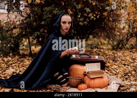 A young woman in the woods practices Halloween magic Stock Photo