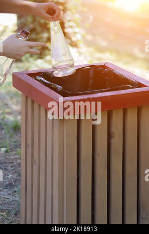 In the hands of two empty glass bottles with a bucket. Ejection of container glass Stock Photo