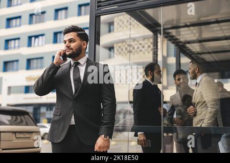 Portrait of a business man outdoors using the phone against the backdrop of a glass building downtown. Stock Photo