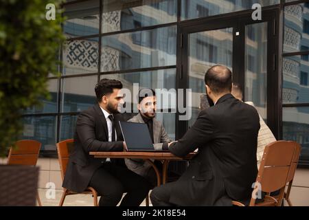 Corporate meeting of business partners outside the office. Male employees sit at the table and discuss the goals, ideas and plans of the company. Stock Photo