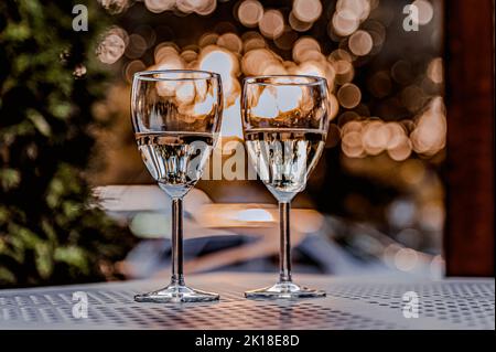 Pair of wine glasses for two persone. Two glasses of champagne on the table against the sunset. Romantic holiday concept. Stock Photo