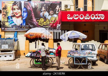 Mysore, Karnataka, India : Two men stand at a stall outside the Olympia cinema in Central Mysore. Stock Photo