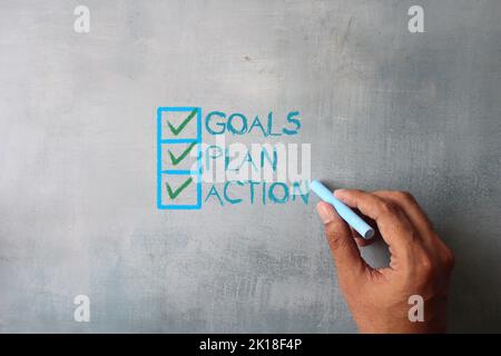 Top view image of hand writing word GOALS, PLAN and ACTION on chalkboard. Business concept Stock Photo