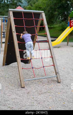 A boy (not recognizable) climbs a rope ladder in a children's park playground Stock Photo