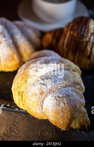 different croissants on a black plate with coffee. Stock Photo
