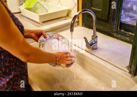 Woman washing dishes in a retro antique style kitchen sink. Stock Photo