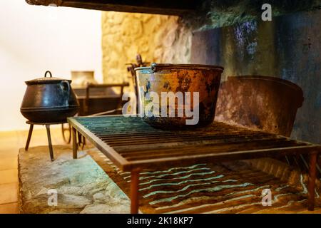 Fireplace with large pots and cooking utensils with fire in an old retro style. Stock Photo