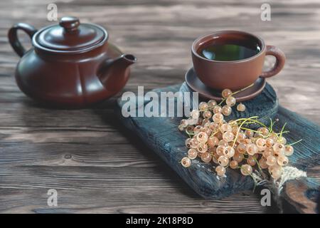 Fortified fruit tea made from berries and leaves of white currant. Berry tea in a ceramic teapot and ceramic teacup. copy space. Stock Photo