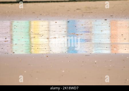 Reflections of multi-coloured beach huts on the wet sand at Walton on the naze Beach in Essex, United Kingdom Stock Photo
