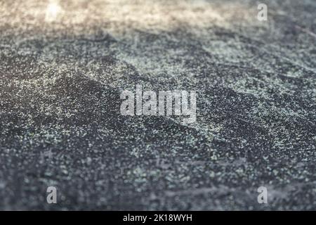 The texture of an old black roofing material . Gray texture background with moss close-up. Stock Photo