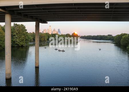 People kayaking and paddleboarding on the Colorado River in Austin Texas as the sunsets view from the Lady Bird Boardwalk Stock Photo