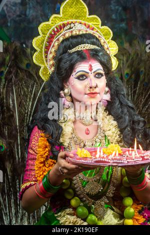 Concept Agomoni shoot with black haired Indian brunette woman face with perfect makeup and wearing jewelers with traditional dress like goddess Stock Photo