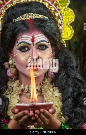 Concept Agomoni shoot with black haired Indian brunette woman face with perfect makeup and wearing jewelers with traditional dress like goddess Stock Photo