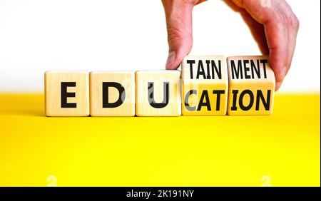 Education and edutainment symbol. Concept words Education and edutainment on wooden cubes. Teacher hand. Beautiful yellow table white background. Educ Stock Photo