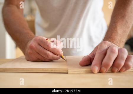 Close up of carpenter hands working on wood craft at workshop to produce construction material or wooden furniture. Professional tools for crafting Stock Photo