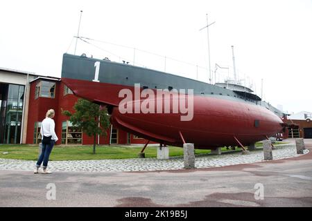 Marinmuseum (previously: Shipyard Museum, Varvsmuseet; alternate: Naval Dockyard Museum; translation: Naval Museum) is a maritime museum located on Stumholmen island, in Karlskrona, Sweden. In the picture: Tourist looking at Sweden's oldest submarine HMS Hajen. Stock Photo