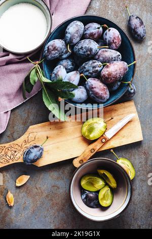 Fresh plums in a bowl and chopped plums on chopping board. Stock Photo