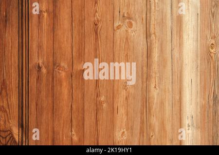 Wooden texture with vertical lines. The texture of wood with knots and holes. The background is made of a wooden fence of natural color. Red wooden background. Stock Photo