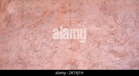 The texture of old painted concrete. The concrete background is dusty pink. The background of a painted wall with cracks. Banner of an old painted plastered wall. Stock Photo