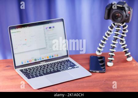Vlogger workplace. Laptop, smartphone and SLR camera on a wooden table. Camera on a mini tripod for vlogging. Video blogging concept Stock Photo