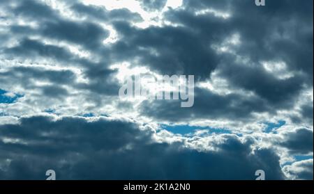 Blue sky with thunderclouds. The sun breaks through the clouds. Black clouds. Banner. Stock Photo