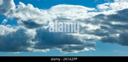 Blue sky with thunderclouds. The sun breaks through the clouds. Black clouds. Banner. Stock Photo