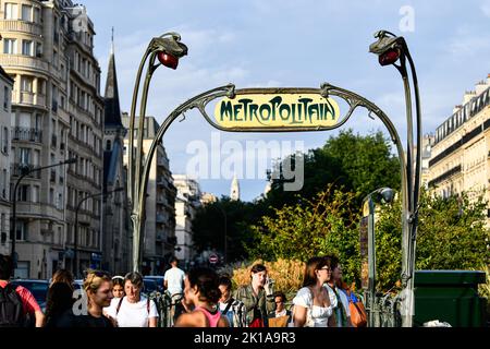 Sign with the subway logo (yellow and green  symbol) in front of a parisian metro (metropolitain) station with a blue sky in the background during a s Stock Photo