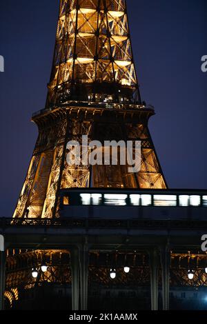 The parisian subway (metro, metropolitain) passes over a bridge with the Eiffel Tower ('Tour Eiffel') in the background at night in Paris, France. Stock Photo