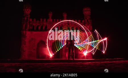 Kodanadu, Tamilnadu, India - March 14 2021 : one person standing against beautiful colorful circle light painting as the backdrop. light painting port Stock Photo