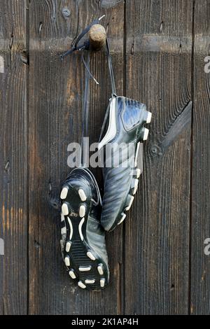 A pair of soccer boots hanging on a wooden wall. The end of the football career Stock Photo