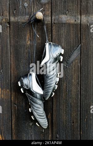 A pair of soccer boots hanging on a wooden wall. The end of the football career Stock Photo