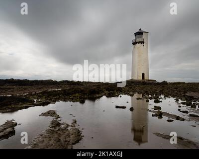 A view of the historic Southerness Lighthouse in Scotland with reflections in tidal pools in the foreground Stock Photo