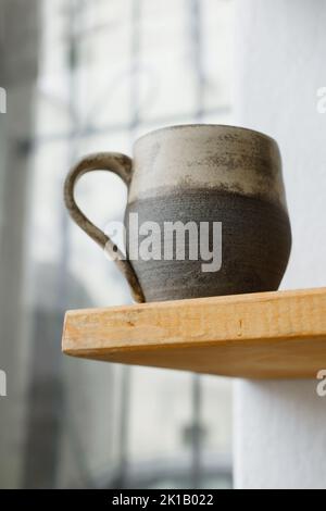 Ceramics with floral and natural patterns on the shelf of the shop. Creative minimalistic handmade cups, mugs and plates. Pottery cutlery earthly Stock Photo