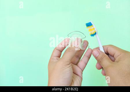 Retainer cleaning care and maintenance concept. Hand holding hawley dental retainers and a toothbrush with copy space. Stock Photo