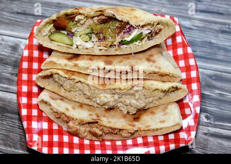 Traditional Egyptian popular breakfast street sandwiches of mashed fava beans, fried crispy falafel balls and baba ghanoush aubergine roast in flat br Stock Photo