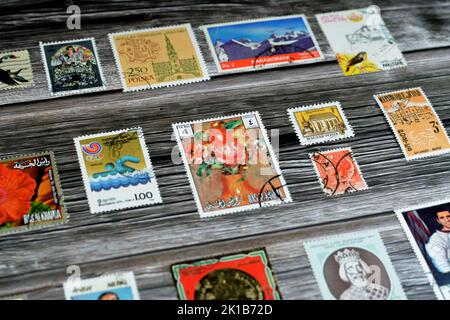 Cairo, Egypt, August 15 2022: Old used historical collection of postage stamps from different countries of the world isolated on wooden background, se Stock Photo