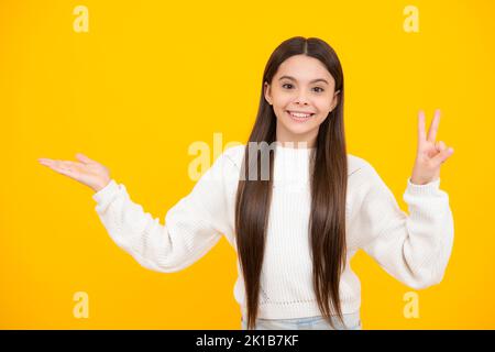 Look at advert. Teenager child points aside shows blank copy space for text promo idea presentation, poses against yellow background. Stock Photo