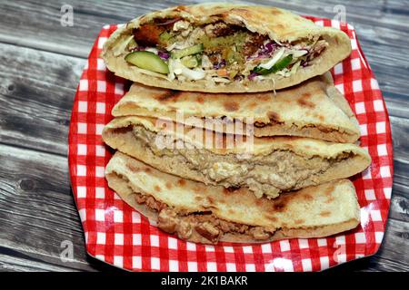 Traditional Egyptian popular breakfast street sandwiches of mashed fava beans, fried crispy falafel balls and baba ghanoush aubergine roast in flat br Stock Photo