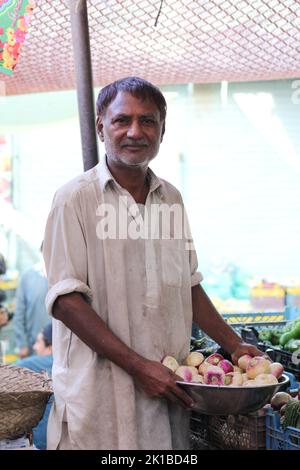 Pakistani salesman in shalwar-kameez attire at the Sunday Market-city's ...